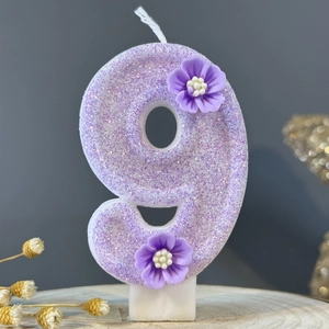 Number 9 birthday candle in purple with glitter finish and small flower decorations