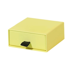 Cream yellow drawer jewelry box with black ribbon pull on a white background