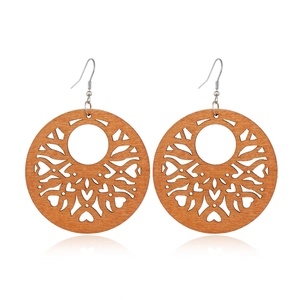 Macro detail of brown hollowed wooden earrings with heart patterns and metal hooks