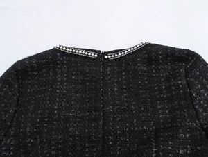 Nahaufnahme von elegantem Tweed-Kleid mit Perlenbesatz am Ausschnitt und Reißverschluss
