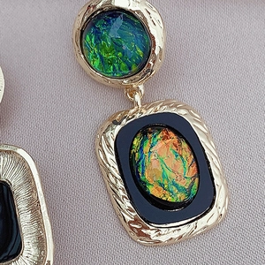 Macro detail of vintage resin geometric earring with gold texture and opal inlay