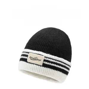 Détail d'un bonnet en maille rayé noir et blanc montrant la texture épaisse et l'étiquette