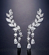 Macro shot of silver leaf-shaped earrings with sparkling cubic zirconia and drop pendants