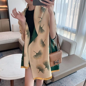 Close-up of double-sided cashmere scarf featuring beige and green ginkgo leaf patterns