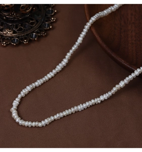 Macro detail of natural freshwater baroque pearl necklace on brown textured fabric