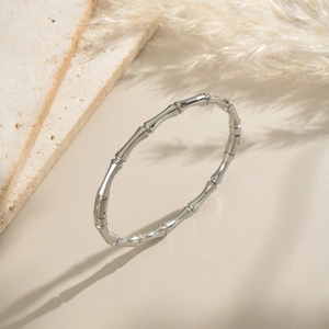 Dettaglio macro del bracciale a bambù argento su pietra dall'estetica minimalista
