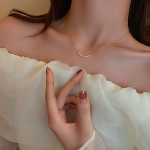 Close-up of a delicate gold necklace with multiple small pearls on a female model