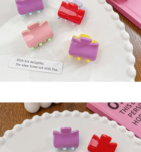 Close-up of colorful candy-colored mini hair claws in a decorative white ceramic tray