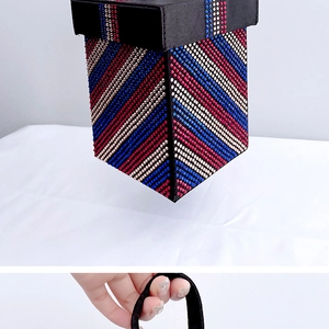 Detail of a black evening bag featuring red, white, and blue rhinestone stripes with handle