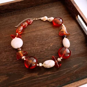 Chic acrylic irregular oval beaded necklace with amber tones on a rustic wooden tray