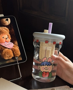 Detail of heat-resistant glass cup with blue lid, purple straw, and cartoon boy print
