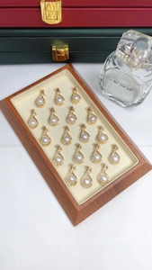 Macro display of eighteen gold-plated freshwater pearl pendants with zircon on wood tray
