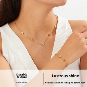Detail view of a gold flower necklace and bracelet set with crystals on a female model