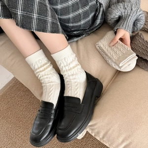Winter cable knit crew socks in white paired with black loafers for a cozy look