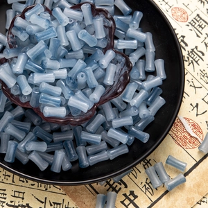 Detailed macro view of frosted blue-grey bamboo-shaped glass beads for jewelry making