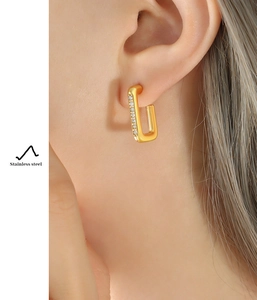 Vue latérale macro de boucles d'oreilles en acier doré en U avec incrustation de zircon
