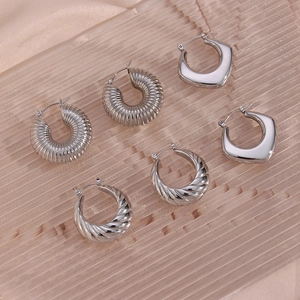 Detailed set of silver geometric and twisted hoop earrings on textured surface