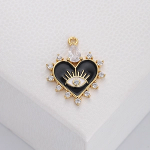 Detail of a golden heart pendant with black enamel evil eye and sparkling zircon stones