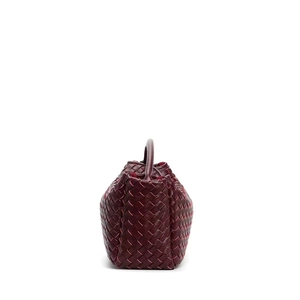 Detailed side view of dark red woven leather handbag with matching arched handle