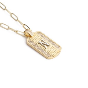 Vue macro d'un pendentif hip-hop doré avec texture tissée et lettre argentée Z