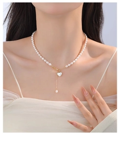 Close-up of natural freshwater pearl necklace with heart shell pendant on model's neck
