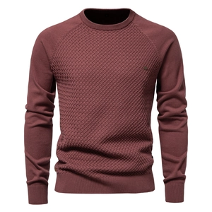 Detail of burgundy knitted sweater featuring textured diamond patterns and ribbed crew neck