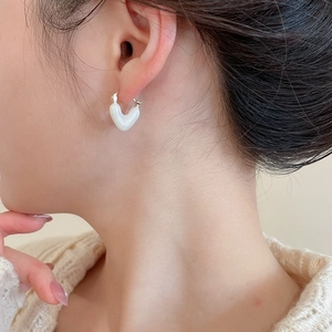 Close-up of elegant heart-shaped pearl earrings in white and gold on a model