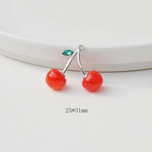 Detail of red cherry pendant with crystal leaves and 25x31mm size text on white surface