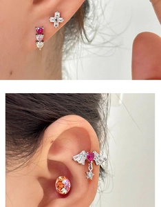 Detail of titanium steel heart and cross earrings on ear for a stylish multi-piercing look