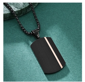 Detail of black military dog tag pendant with rose gold stripe on textured surface