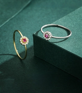 Dettaglio di anelli in argento e oro con pietre rosse quadrate su basi geometriche