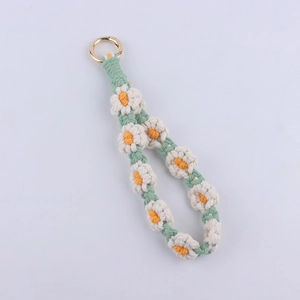 Detail of hand-woven daisy flower keychain with green cotton cord and golden metal ring