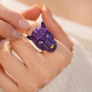 Gros plan d'une bague tête de panthère violette unique avec des pois roses et un design audacieux