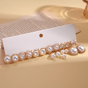 Close-up of vintage gold earrings set with pearls and rhinestones on white display card