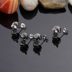 Detailed view of skull earrings with rhinestone eyes on a reflective black stone surface