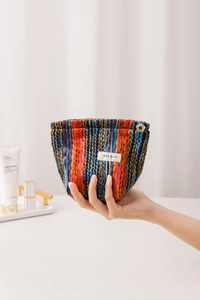 Detail of bohemian striped knit makeup bag with flower zipper pull and logo label