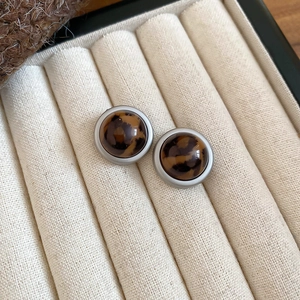 Detailed view of leopard print round stud earrings set in a beige velvet jewelry box