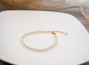 Detailed shot of handmade freshwater pearl bracelet with gold spacers and extension chain
