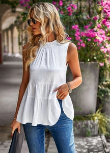 Detail view of a white sleeveless tiered top with textured jacquard fabric in a natural setting