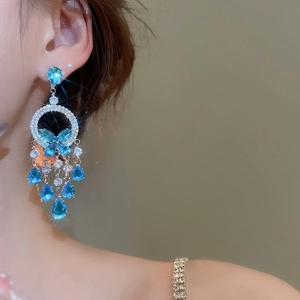 Macro view of crystal tassel earrings with blue teardrop stones and butterfly motif