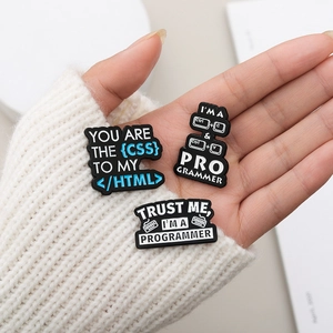 Three-piece programmer enamel pins featuring CSS HTML and Ctrl CV code design on a palm