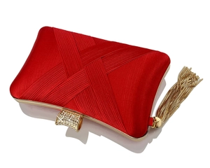 Close-up of red satin evening clutch with woven texture, crystal buckle, and gold tassels
