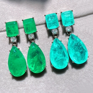 Macro view of teardrop emerald-style earrings with pear-shaped and rectangular gems