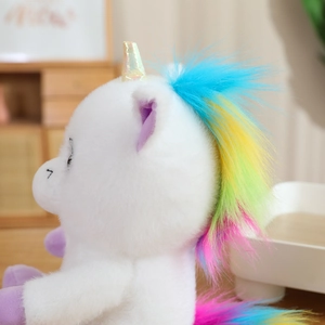 Close-up of soft white unicorn plush with golden spiral horn and rainbow mane details