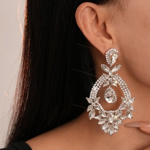 Close-up of luxury floral drop earrings with sparkling rhinestones worn by a model