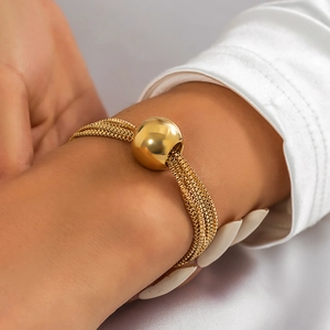 Detail of layered gold chain bracelet with large spherical bead on a wrist model