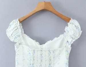 Detail of white floral puff sleeve top with elastic smocking and ruffle trim