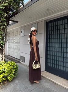 Detail of a brown strapless maxi dress styled with a gold pleated textured handbag