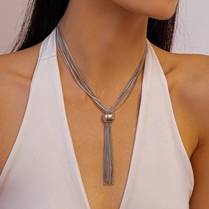 Détail du collier à chaînes argentées multicouches avec boule centrale et longs pompons