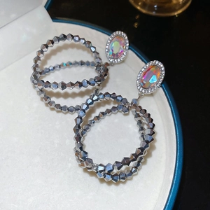 Détail de boucles d'oreilles double cercle argentées avec pierres irisées et micro-pave cristaux